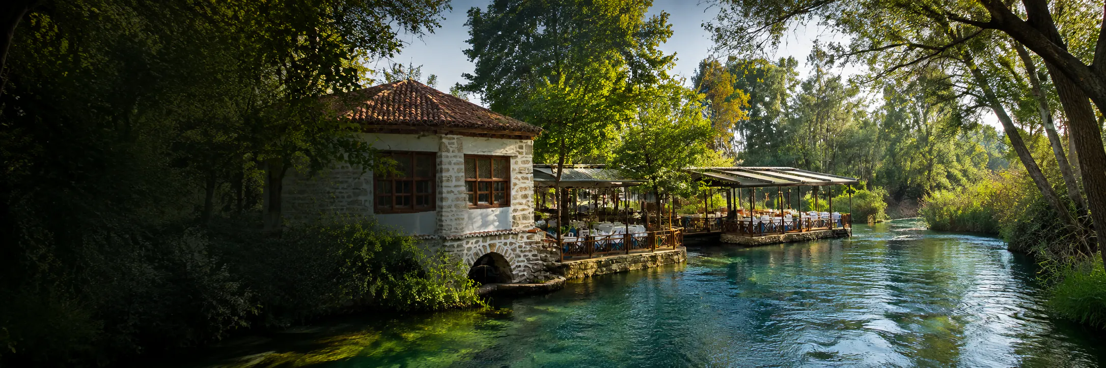 Taş değirmen binası ve ağaçların altındaki nehir kenarı terası, Azmak Başı